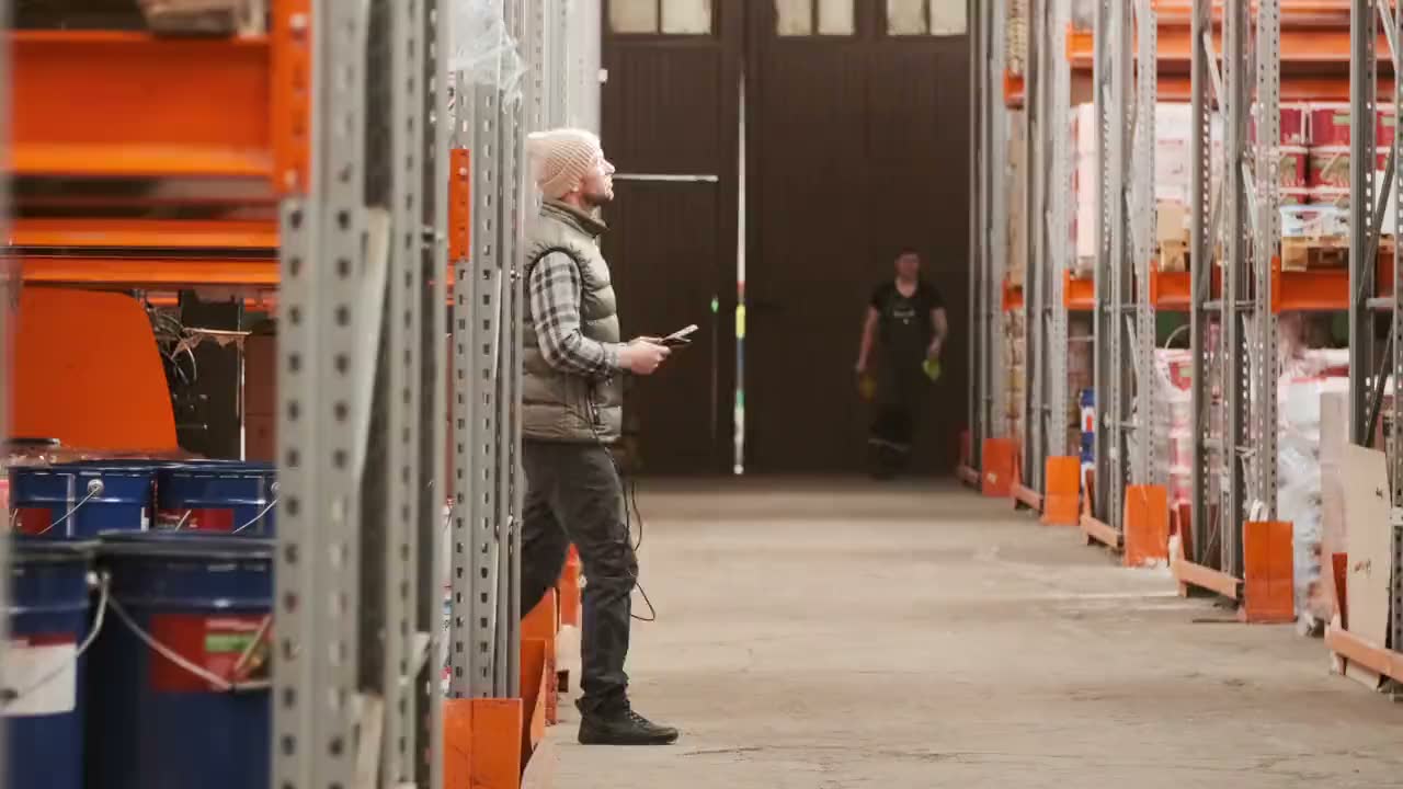 Worker reviewing inventory on a tablet in an industrial warehouse
